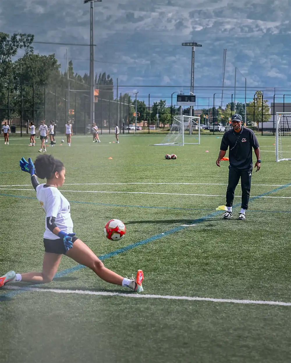 Coach observing a young goalkeeper during a training drill