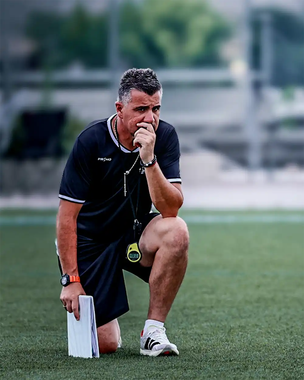 Coach kneeling with a whistle during a training session