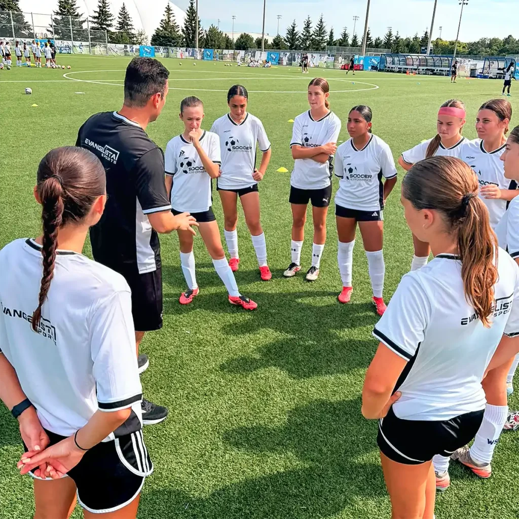 Coach instructing a group of players on the pitch